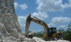 A digger claws away on sloping edges of the Mayan pyramid in Belize